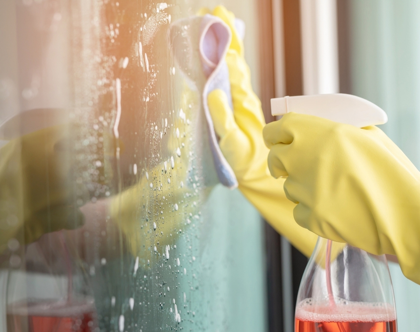 Fensterreinigung mit gelben Handschuhen und Sprühflasche